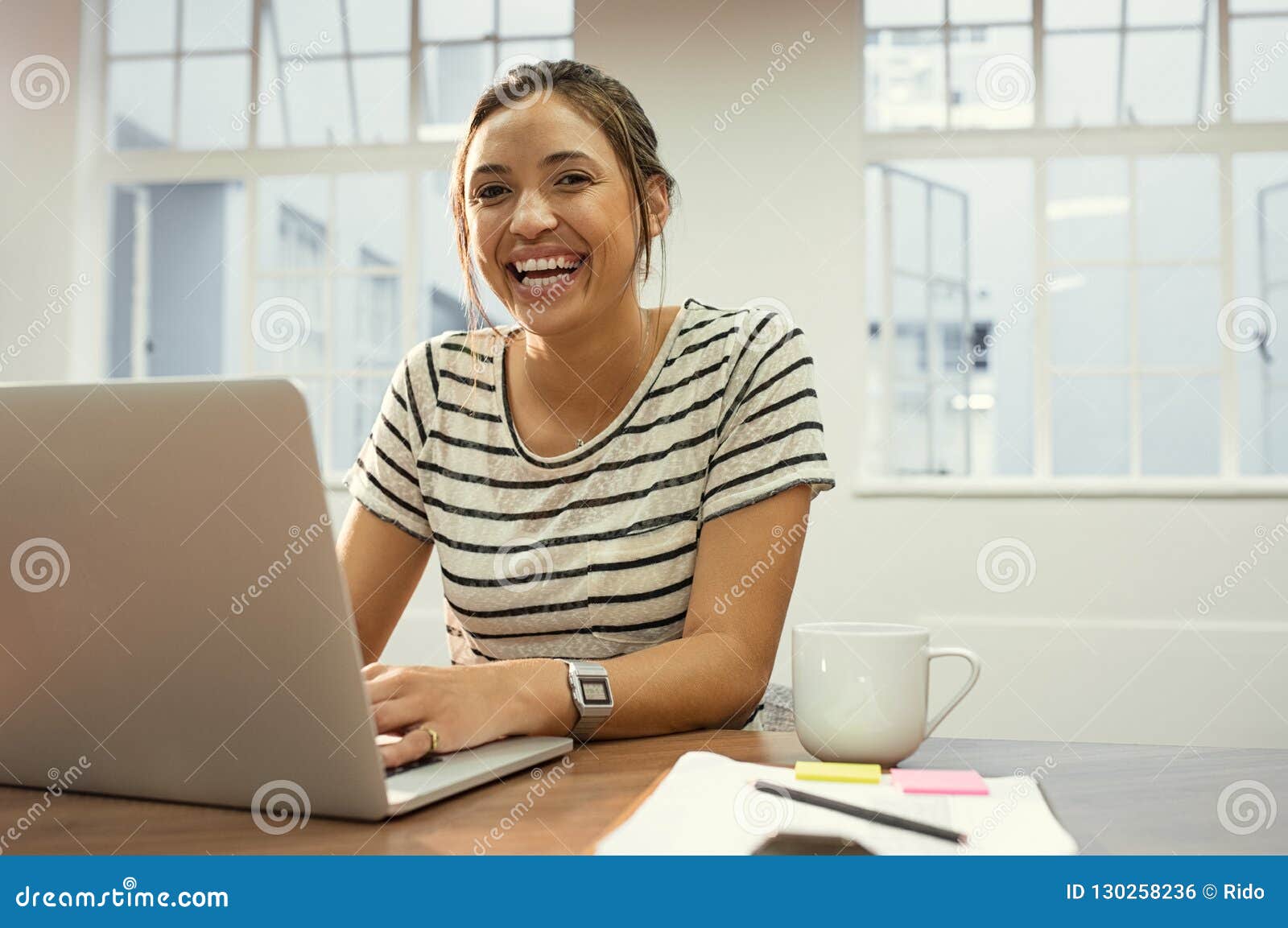cheerful latin woman using laptop