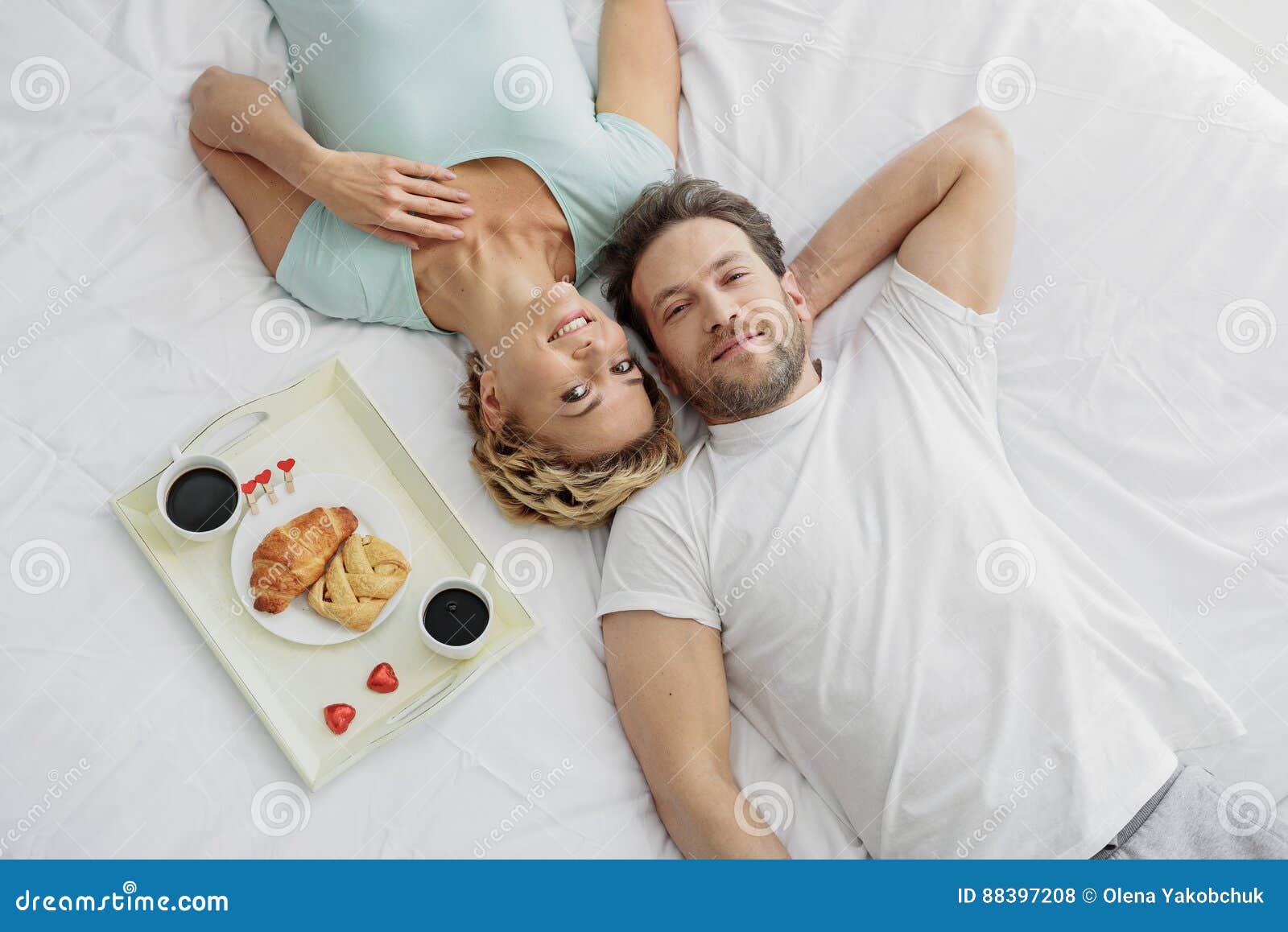 Cheerful Married  Couple  Lying On Bed  Near Breakfast Stock 