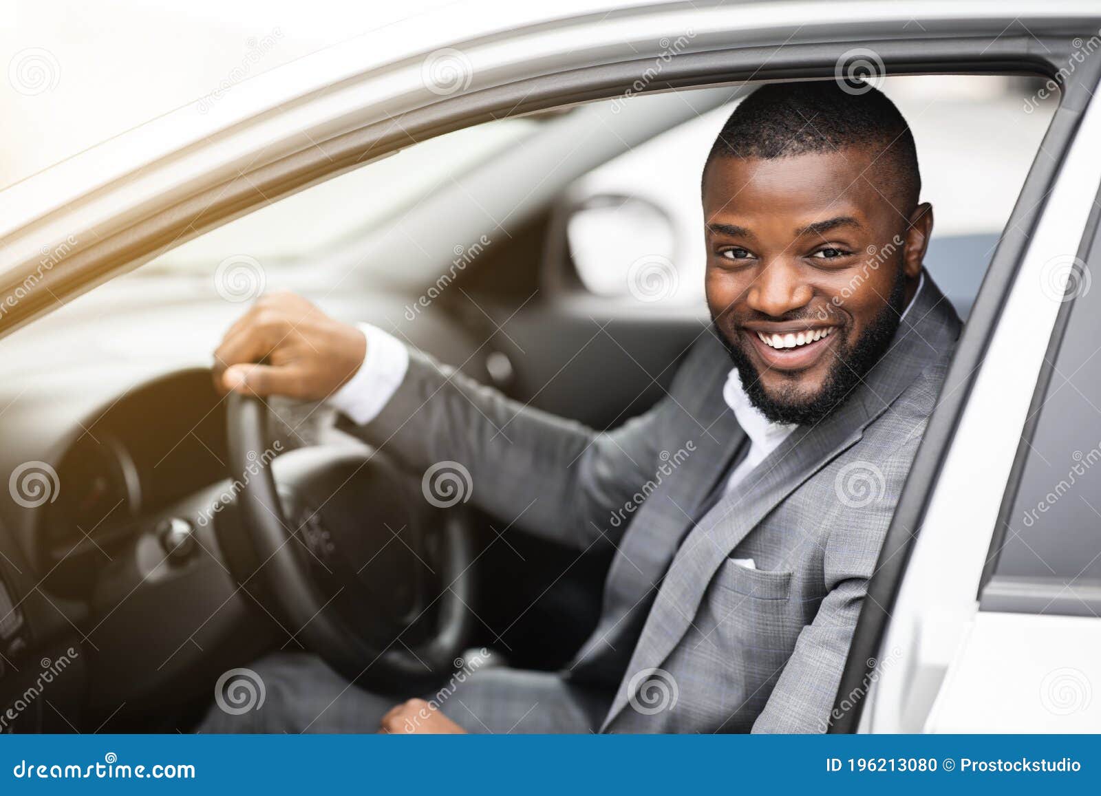 cheerful successful black businessman looking through car window