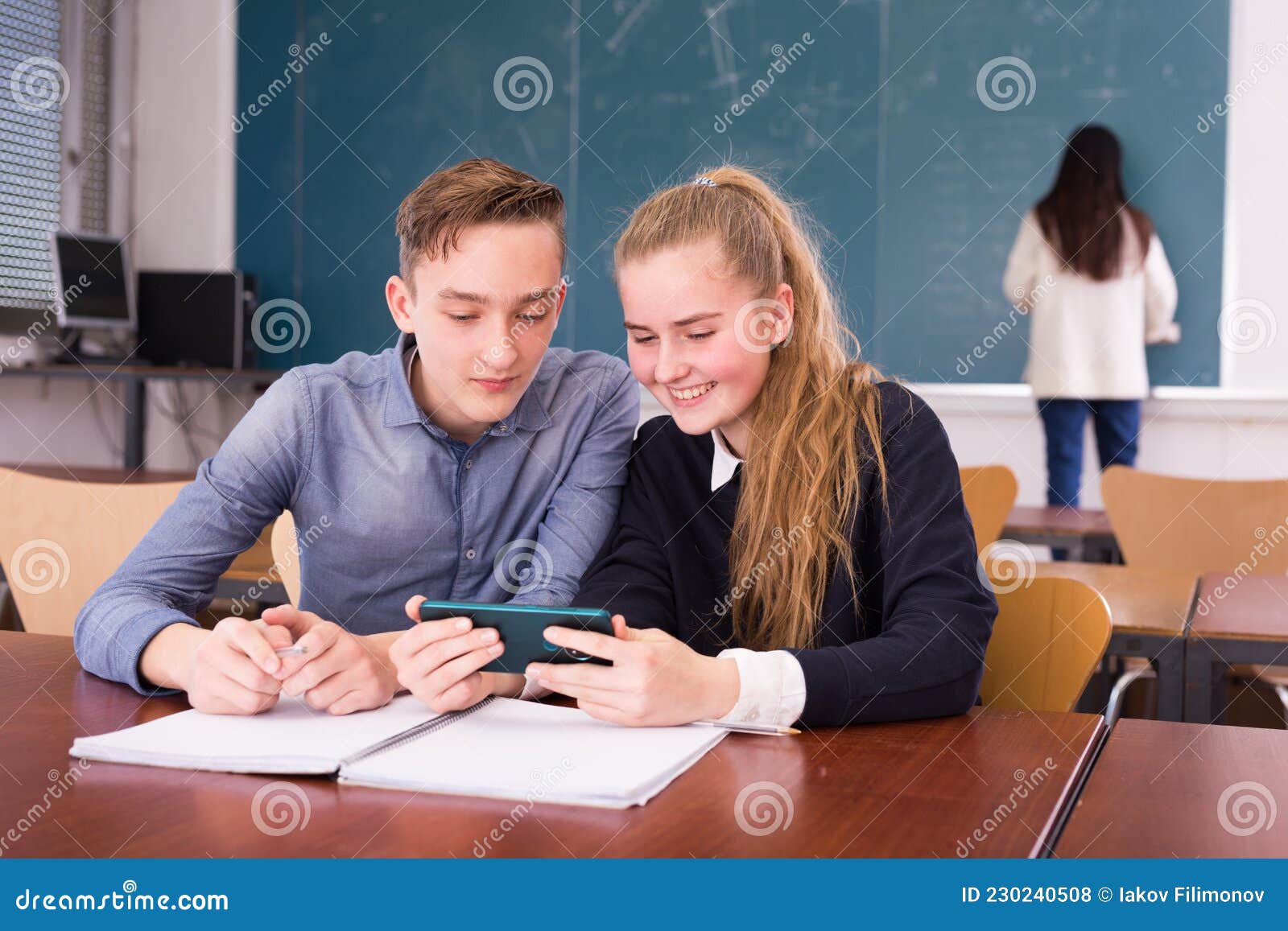 cheerful teenagers with phone in schoolroom