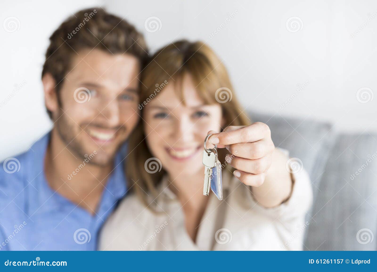 cheerful thirty year old couple showing a keys of their new apartment