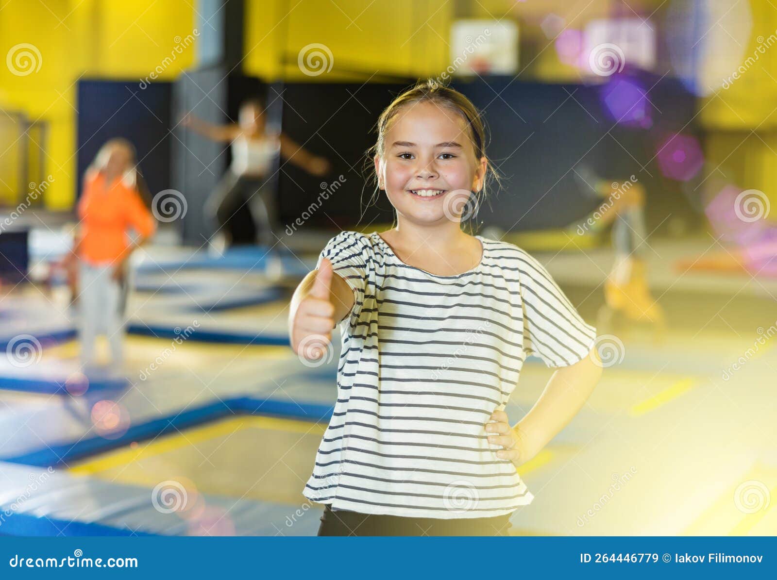 Cheerful Tween Girl Giving Thumbs Up On Trampolines In Inflatable