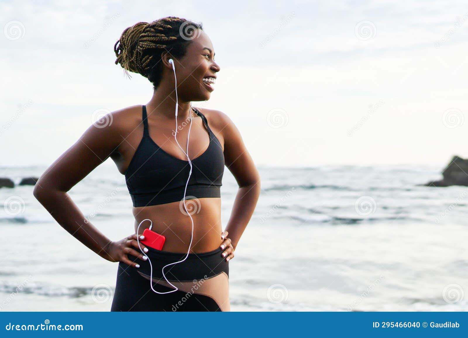 Woman in black sports bra and track pants running at beach HD