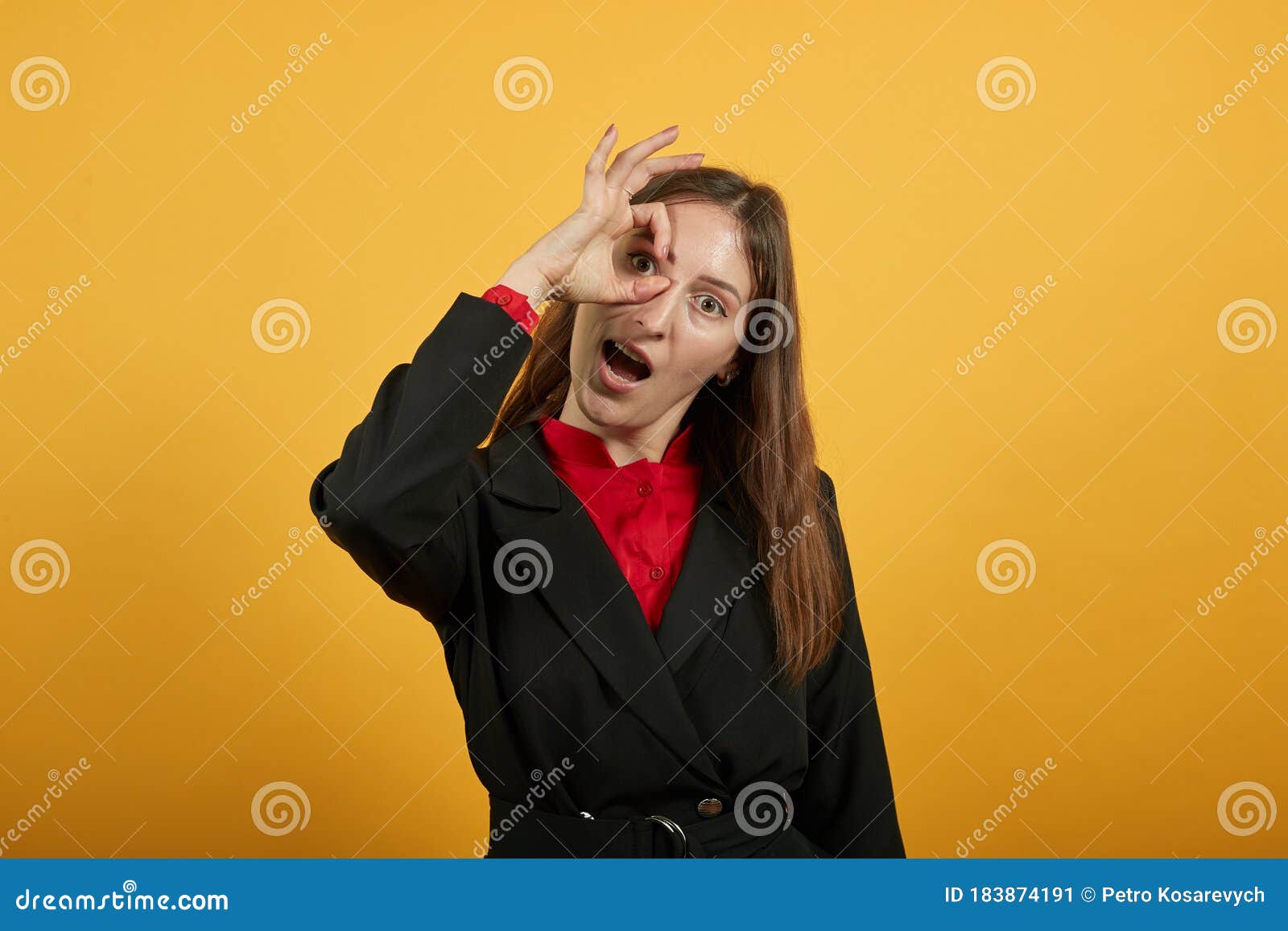 cheerful woman holds fingers to eye as a sign that everything is ok with her.