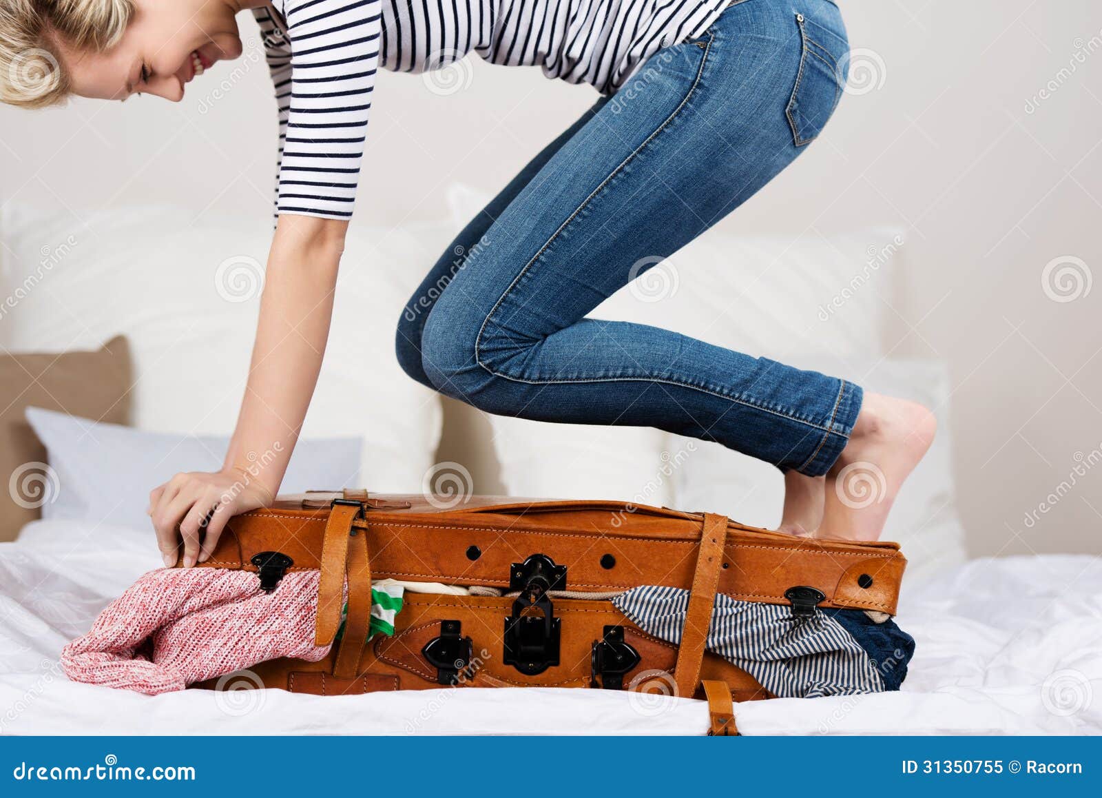 Crop woman packing suitcase on bed - a Royalty Free Stock Photo