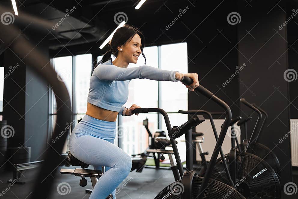 Cheerful Woman Riding on Exercise Bike. Cardio Workout in the Gym