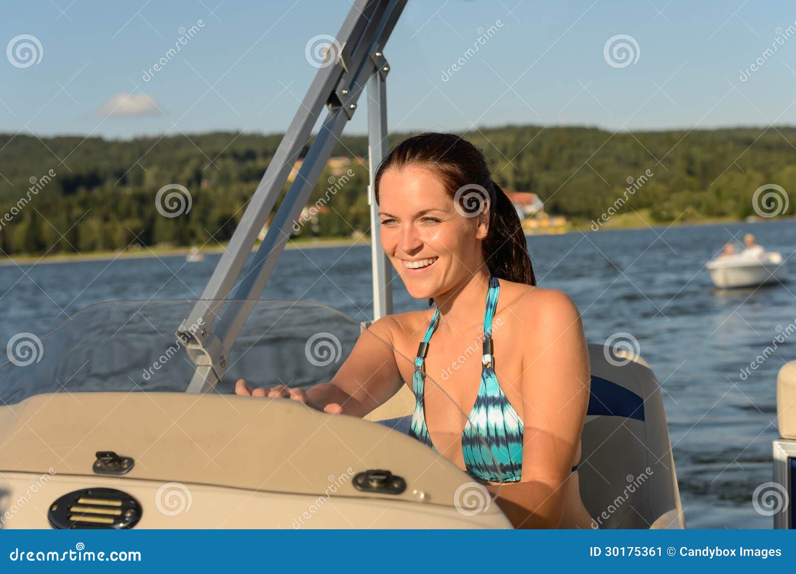 cheerful woman navigating powerboat in summer