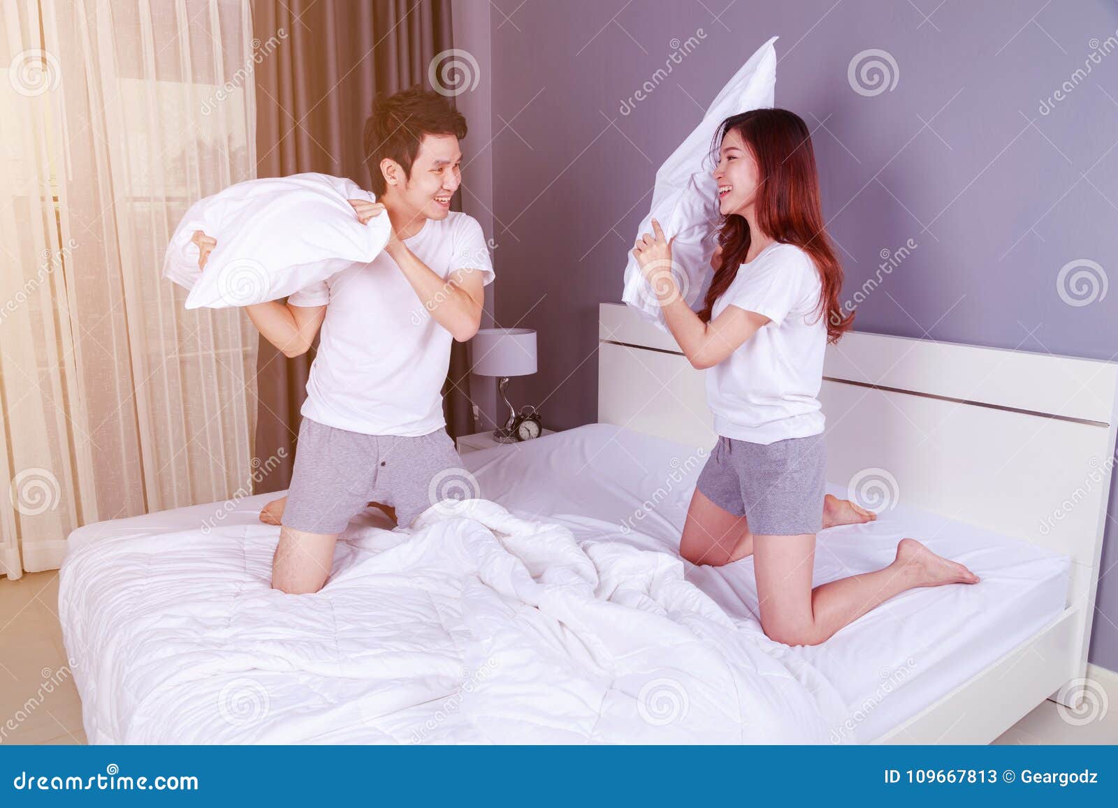 Cheerful Young Couple Having A Pillow Fight On B