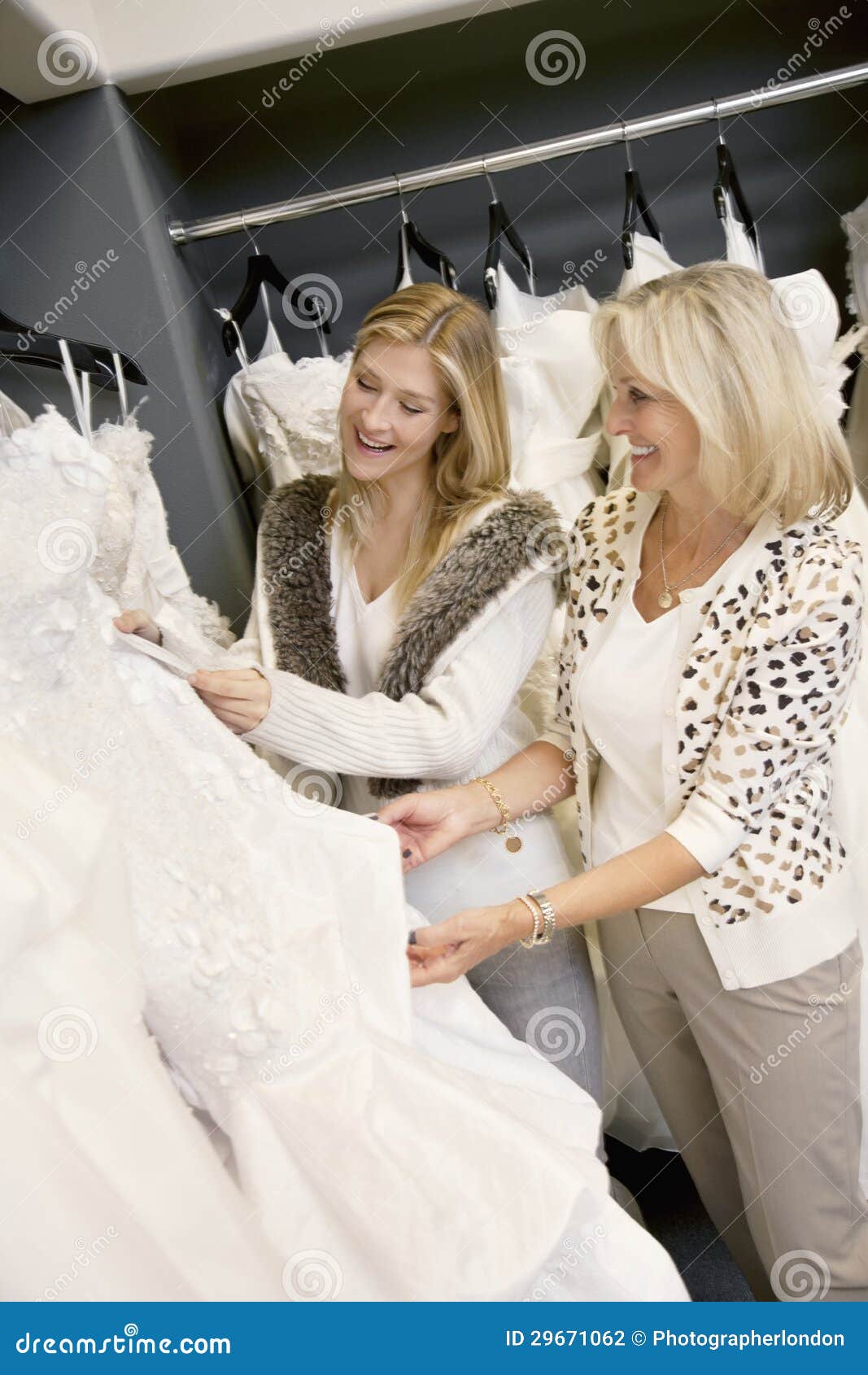 cheerful young daughter with senior mother selecting wedding dress in bridal boutique