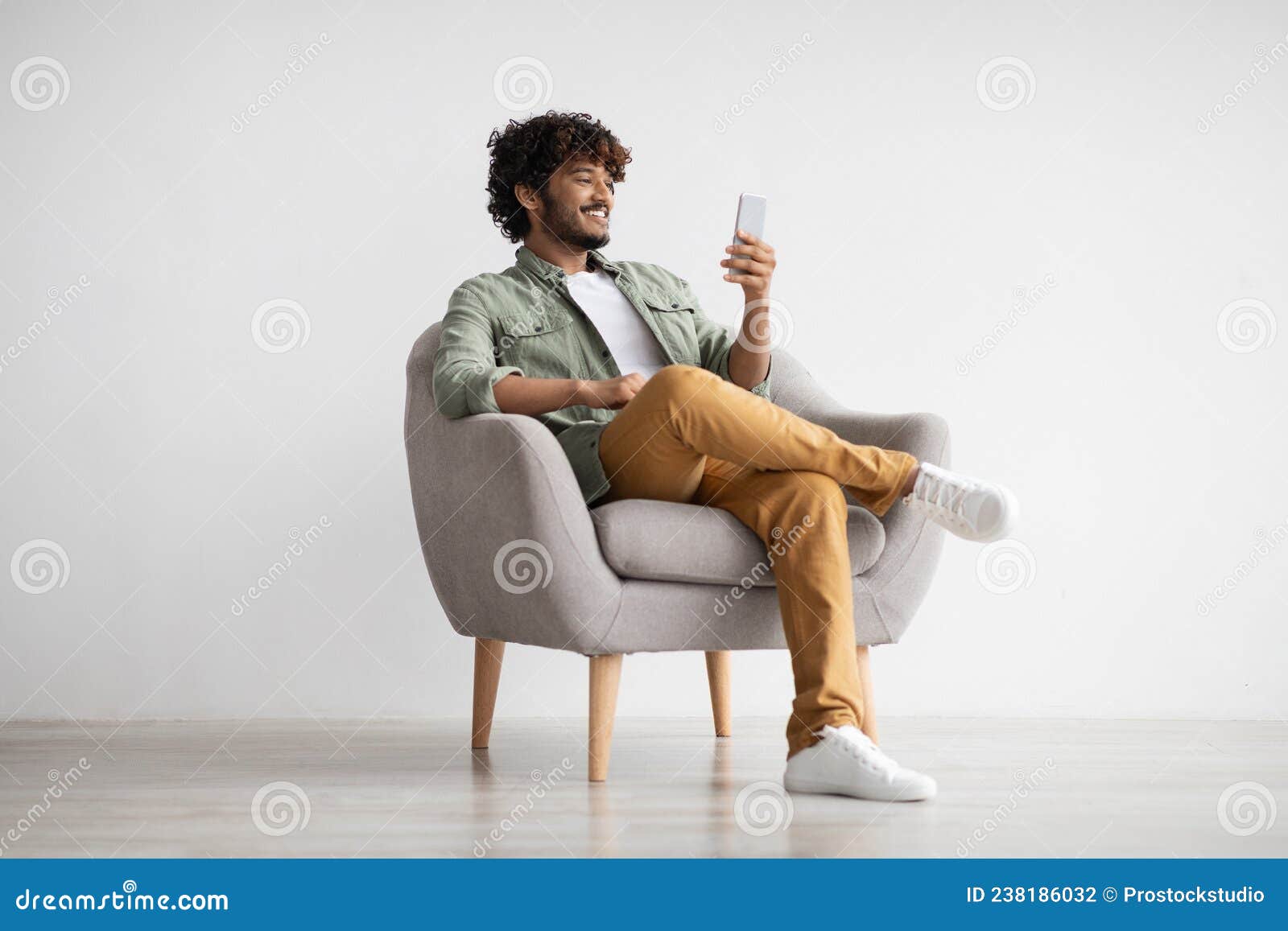 cheerful young indian man chatting with girlfriend, using smartphone