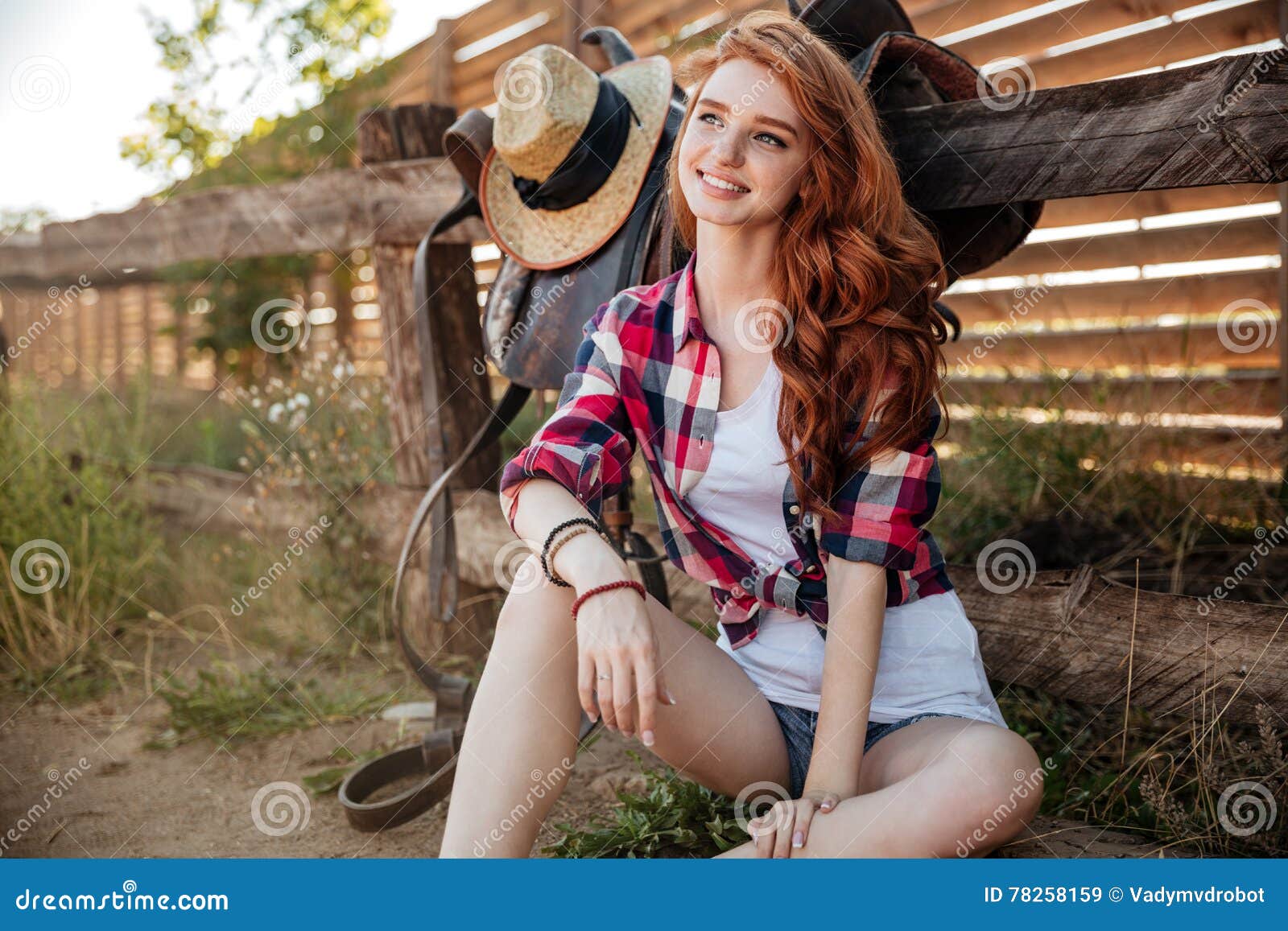 Cheerful Young Woman Cowgirl Sitting And Smiling Outdoors Sto