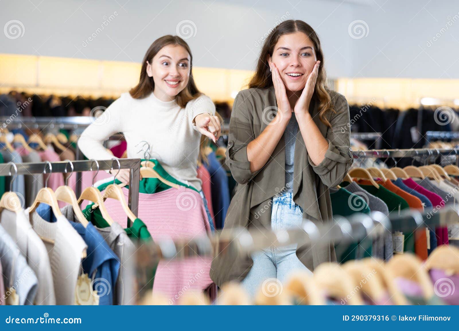 Amazed Female Holding Warm Clothes on Hangers and Showing Her Friend a ...