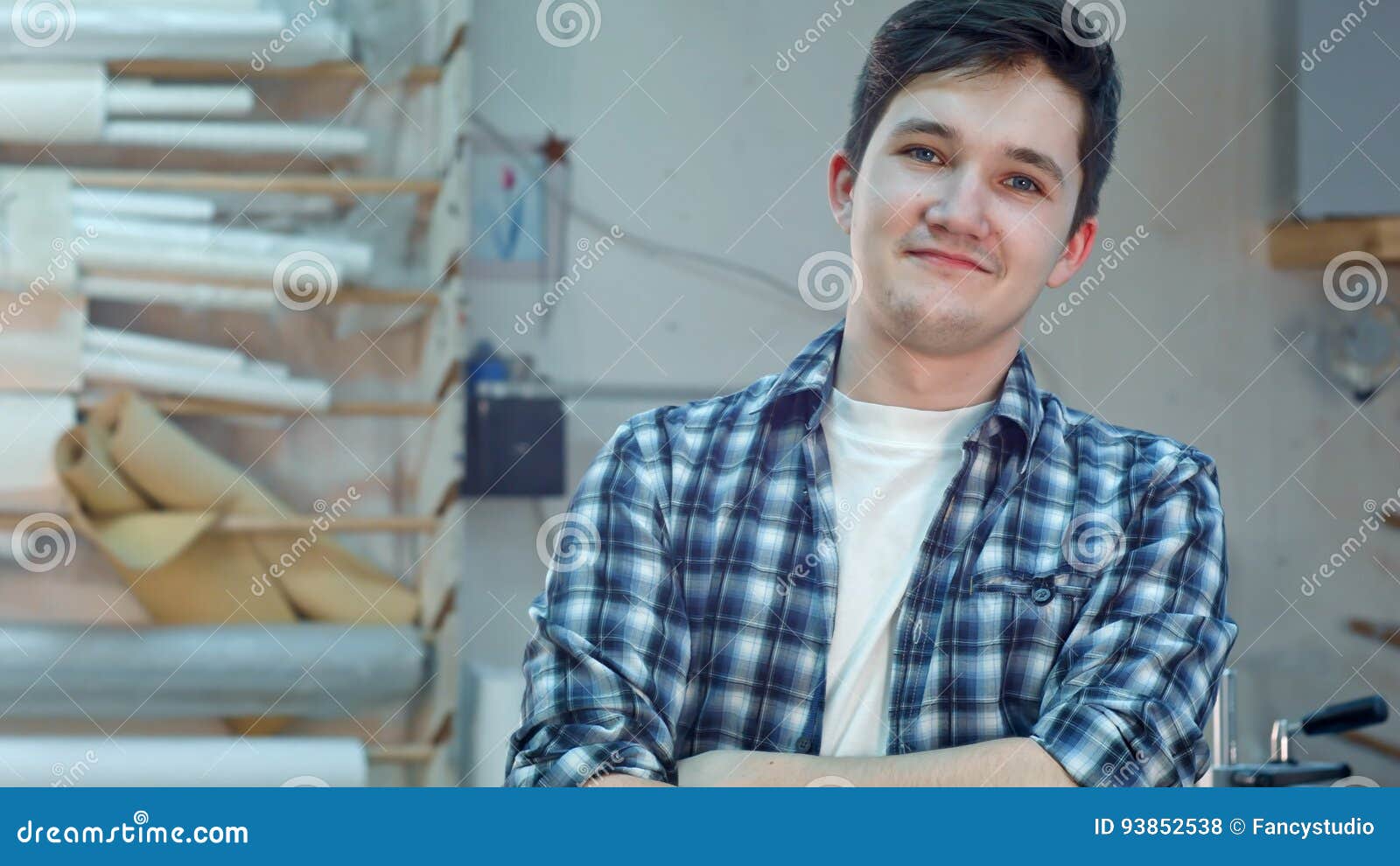 cheerful young workrer in a frame atelier workshop smiling and looking at camera