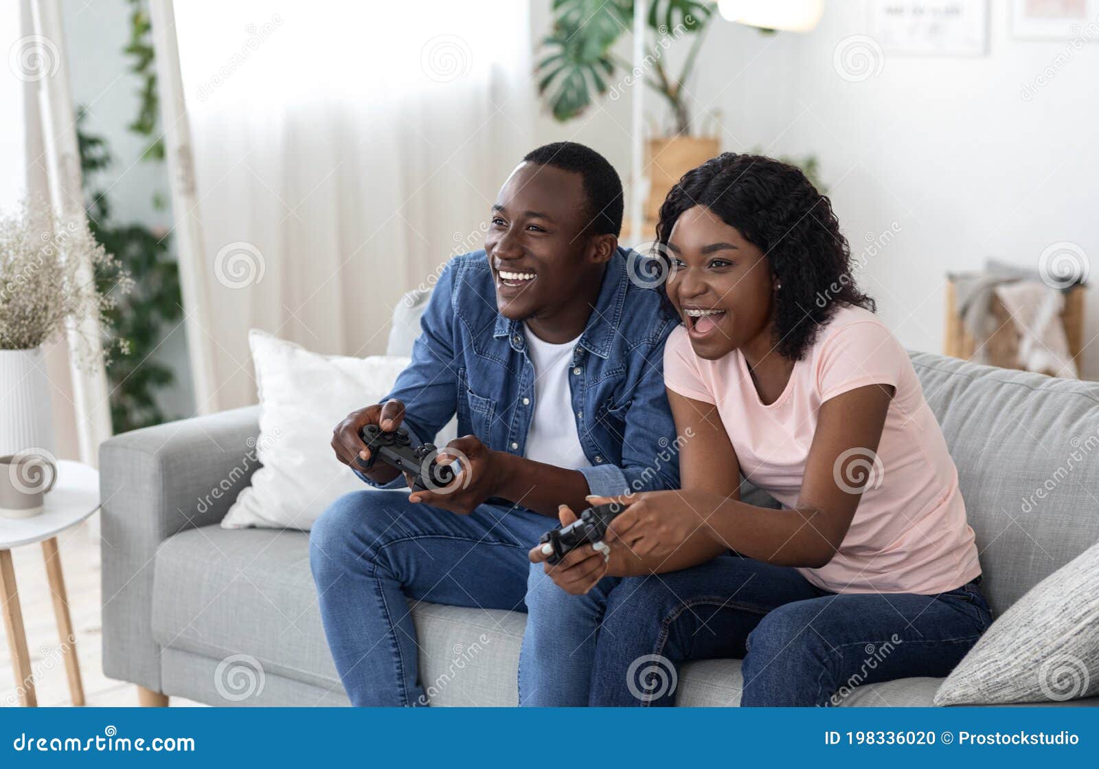 Happy Couple Sitting On The Sofa Playing Video Games Using