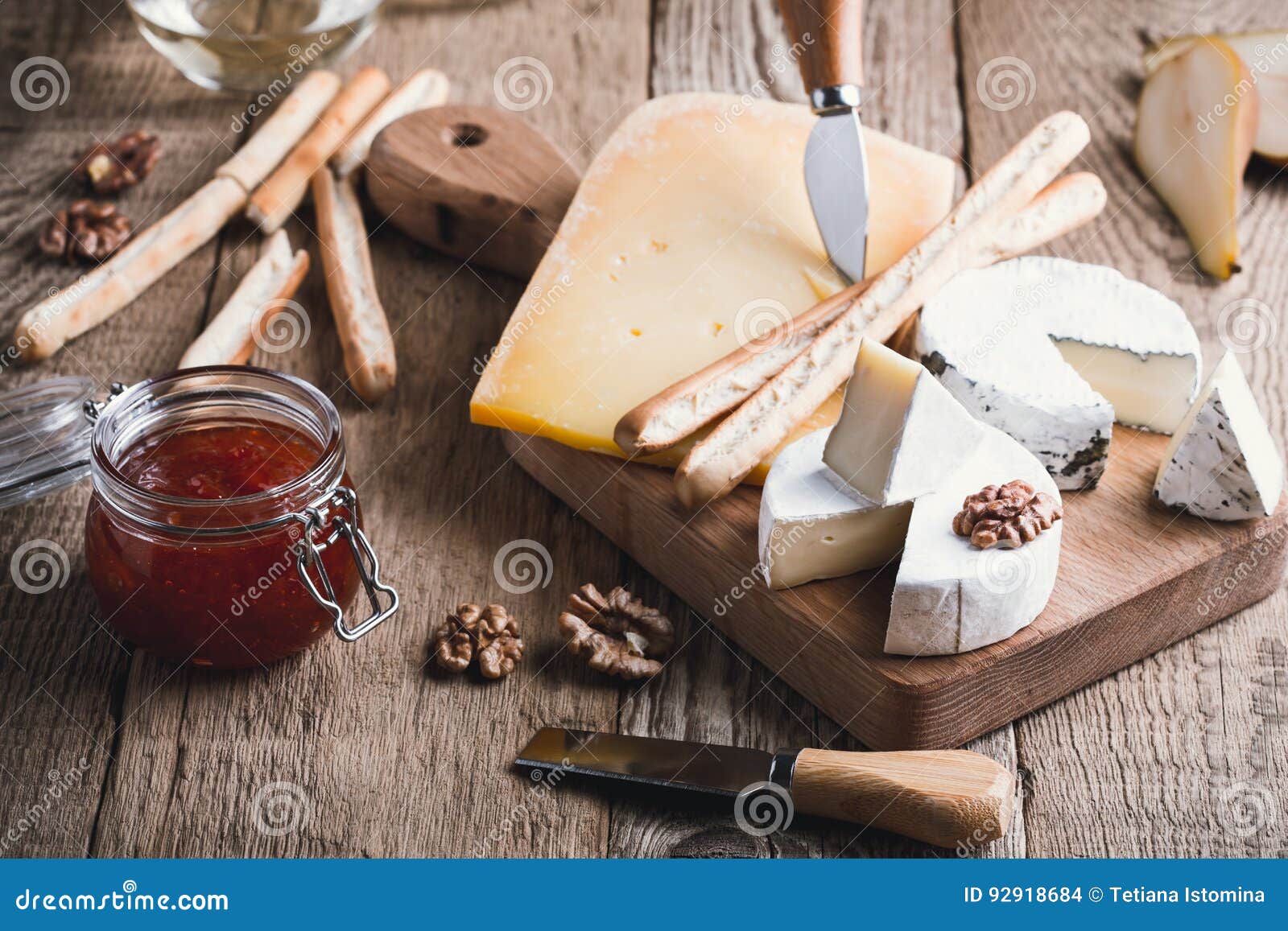 Cheese Platter with Wine, Jam and Walnuts on Wooden Board Stock Photo