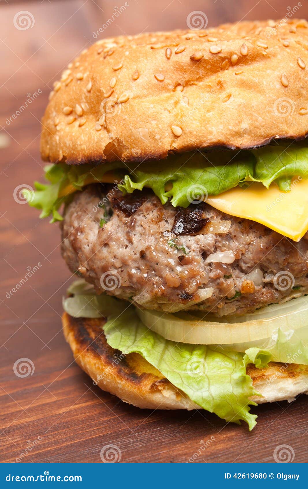 Cheeseburgerclose-up op houten lijst. Grote smakelijke cheeseburger op het close-up van het sesambroodje op houten lijst