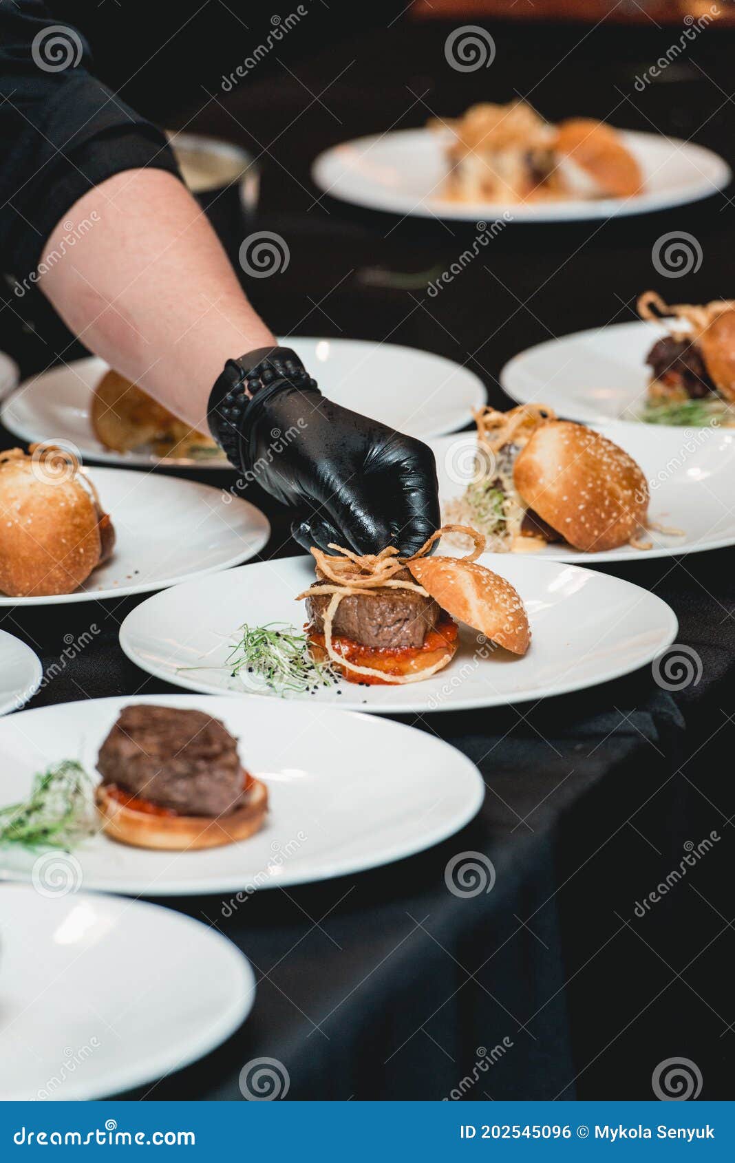 Chef in a Black Gloves Serving a Burgers on the Table in a Restaurant