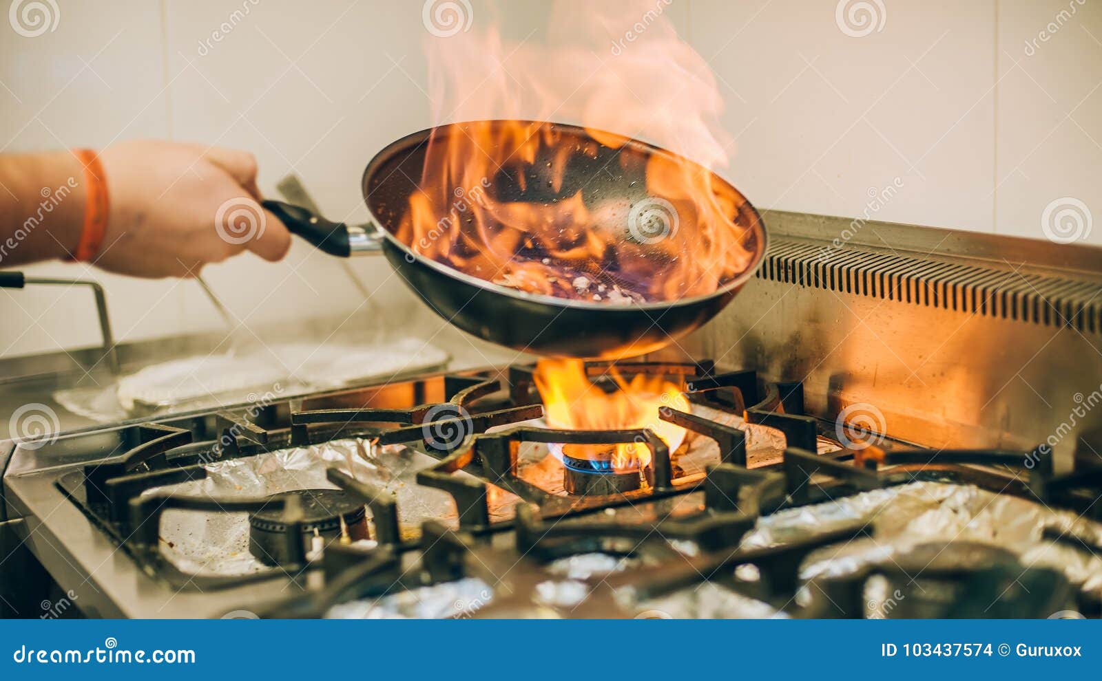 Unrecognizable man cooking in fatiscent big pan or wok in a small