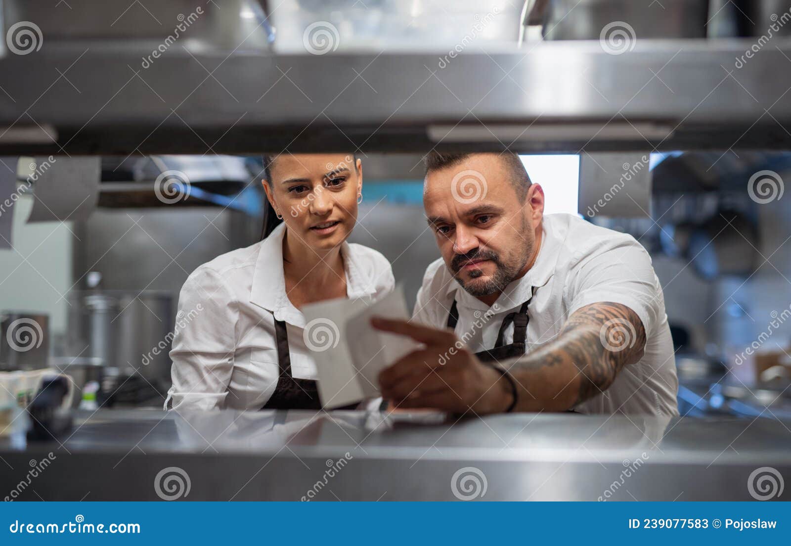 Chef and Cook Taking Order Slip in Commercial Kitchen. Stock Image
