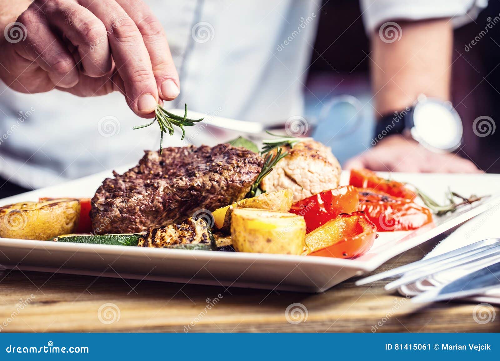 chef in hotel or restaurant kitchen cooking only hands. prepared beef steak with vegetable decoration