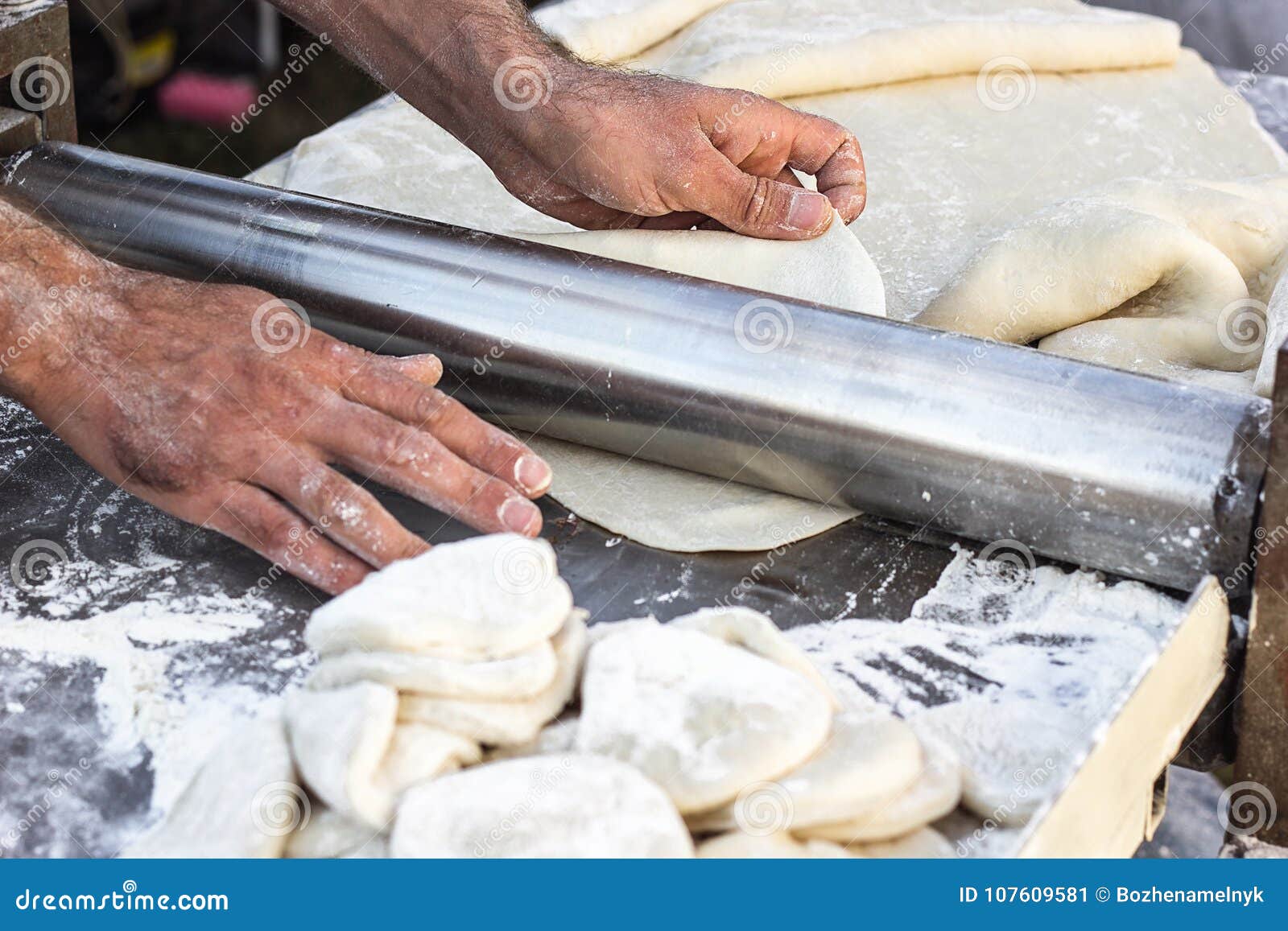 chef making dough pastry sheeter at bakery baker forming shaping dough rolled pastry metal work table closeup hands process of pre