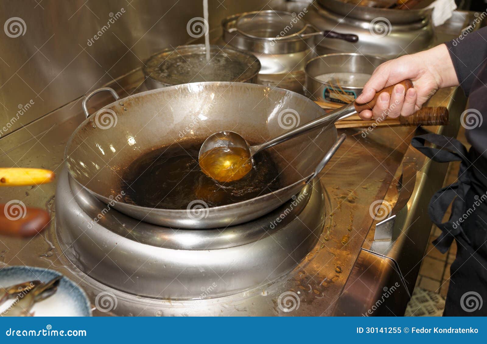 Unrecognizable man cooking in fatiscent big pan or wok in a small