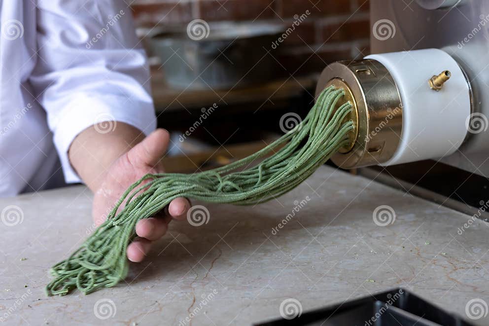 Chef Prepares Green Noodles Using a Pasta Machine in a Trendy Kitchen