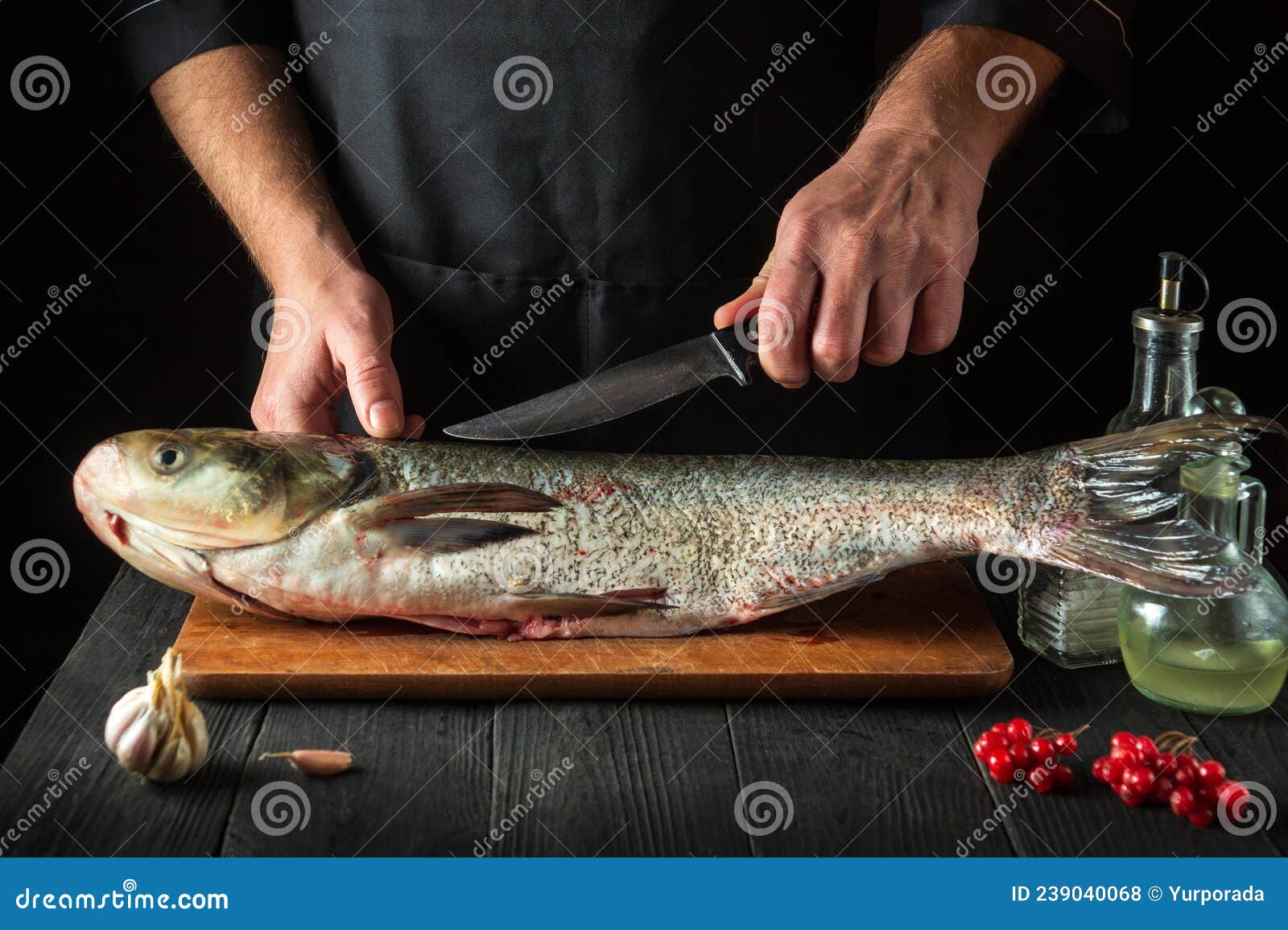 the chef prepares silver carp herring in the restaurant kitchen. preparation for cutting fish with a knife. work environment on