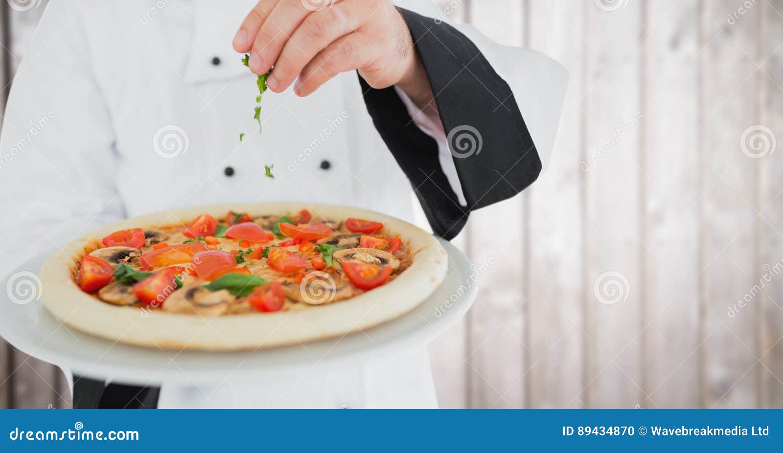 Chef Putting Herbs on Pizza Against Blurry Wood Panel Stock Photo ...