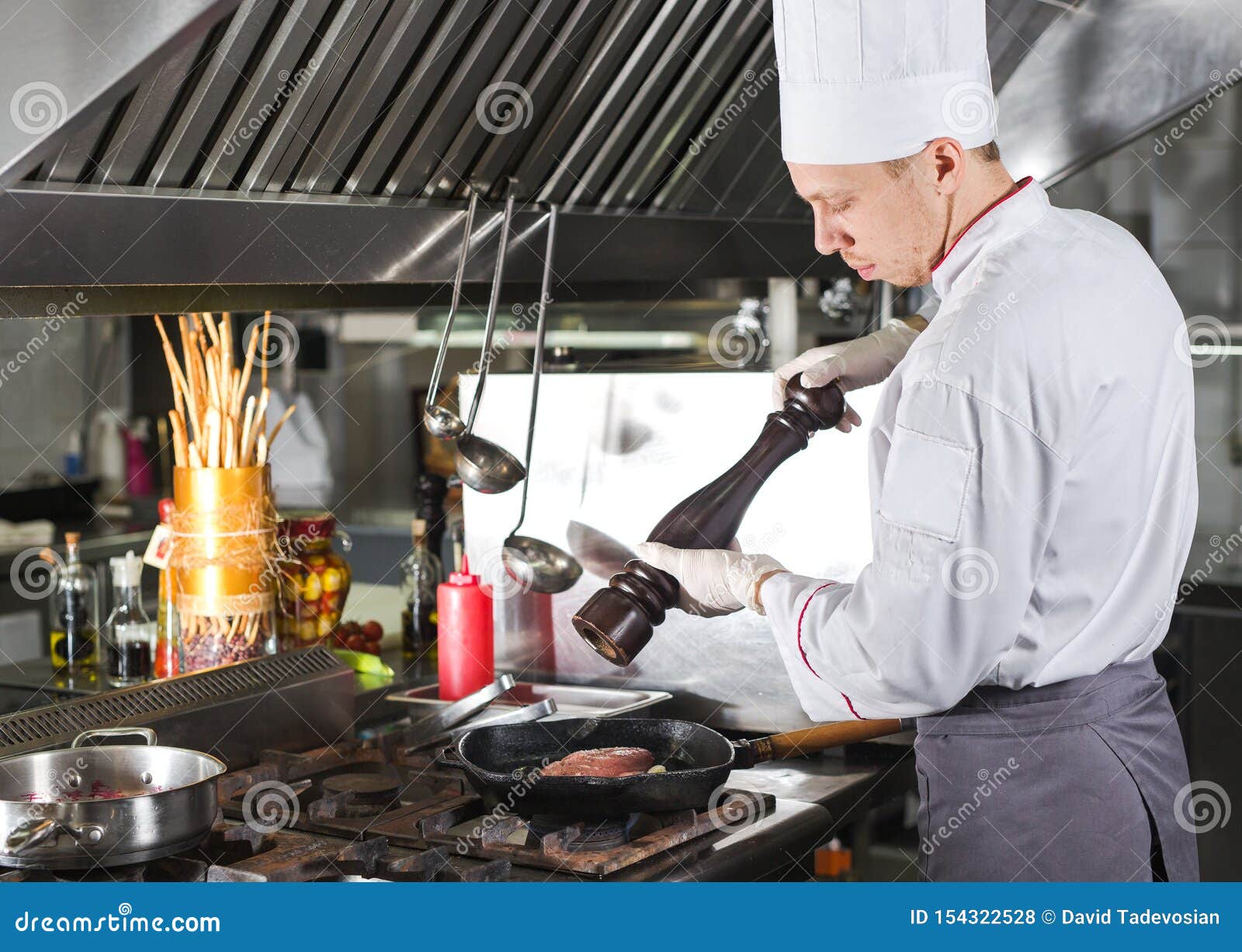 Chef in Restaurant Kitchen at Stove with Pan, Cooking Stock Photo
