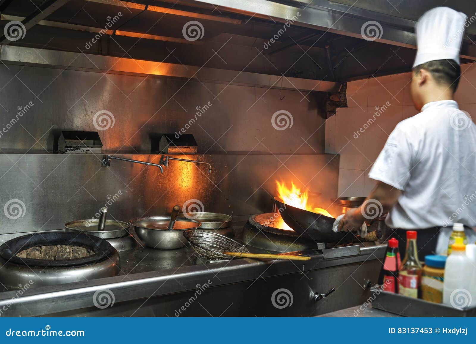 Chef in Restaurant Kitchen at Stove with Pan Editorial Stock Photo