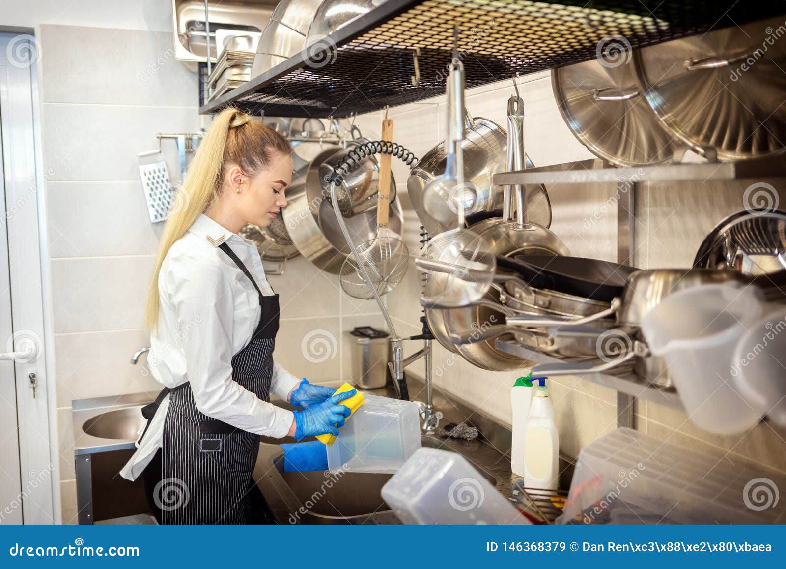 chef of small restaurant washing dishes in sink at end of working day Ã¢â¬â kitchen worker using sponge to clean dishes