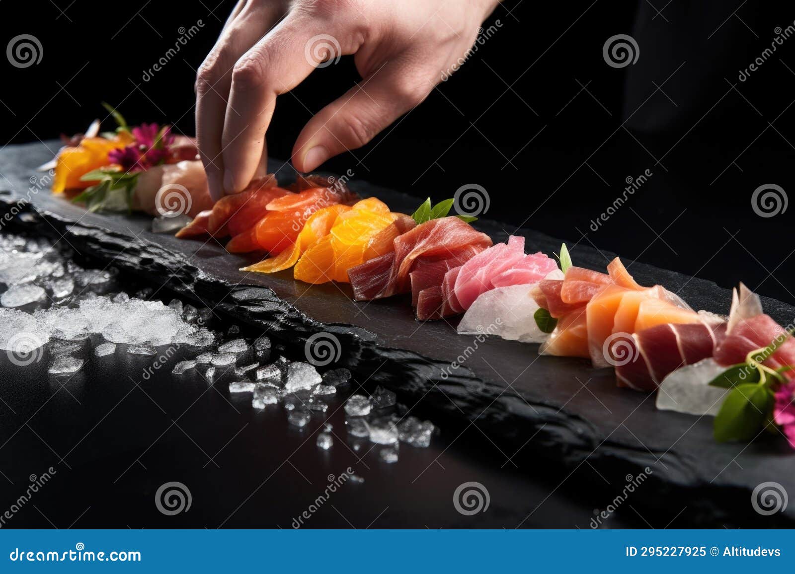 Chefs Hand Elegantly Fanning Sushi on a Black Slate Plate Stock Image