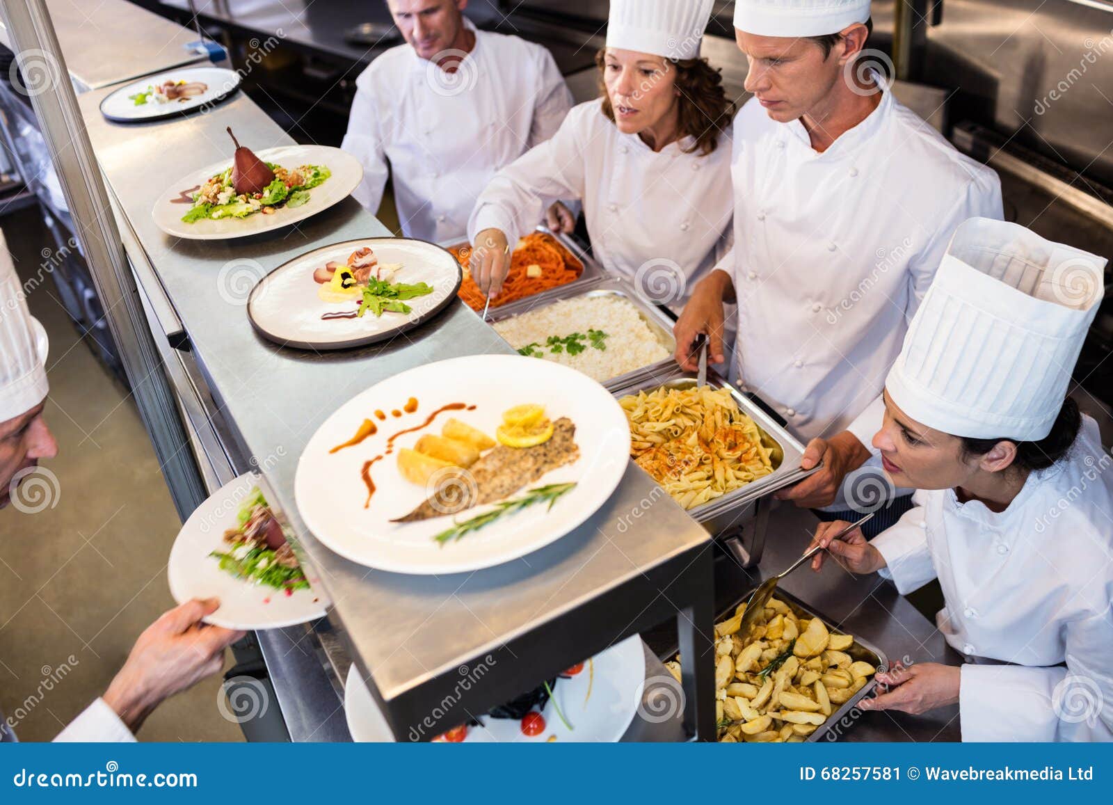 Chefs Handing Dinner Plates through Order Station Stock Image Image