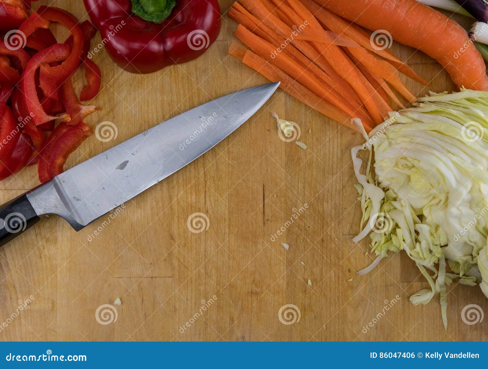 Chefs Knife Rests on Cutting Board with Cut Vegetables Stock Photo