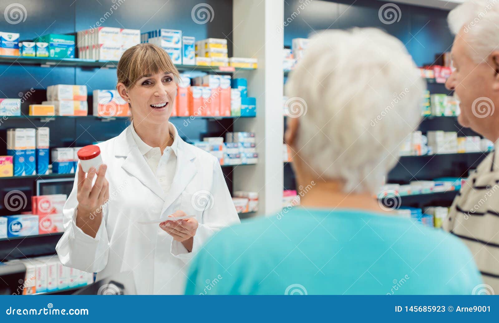 chemist advising senior couple on a drug in her pharmacy