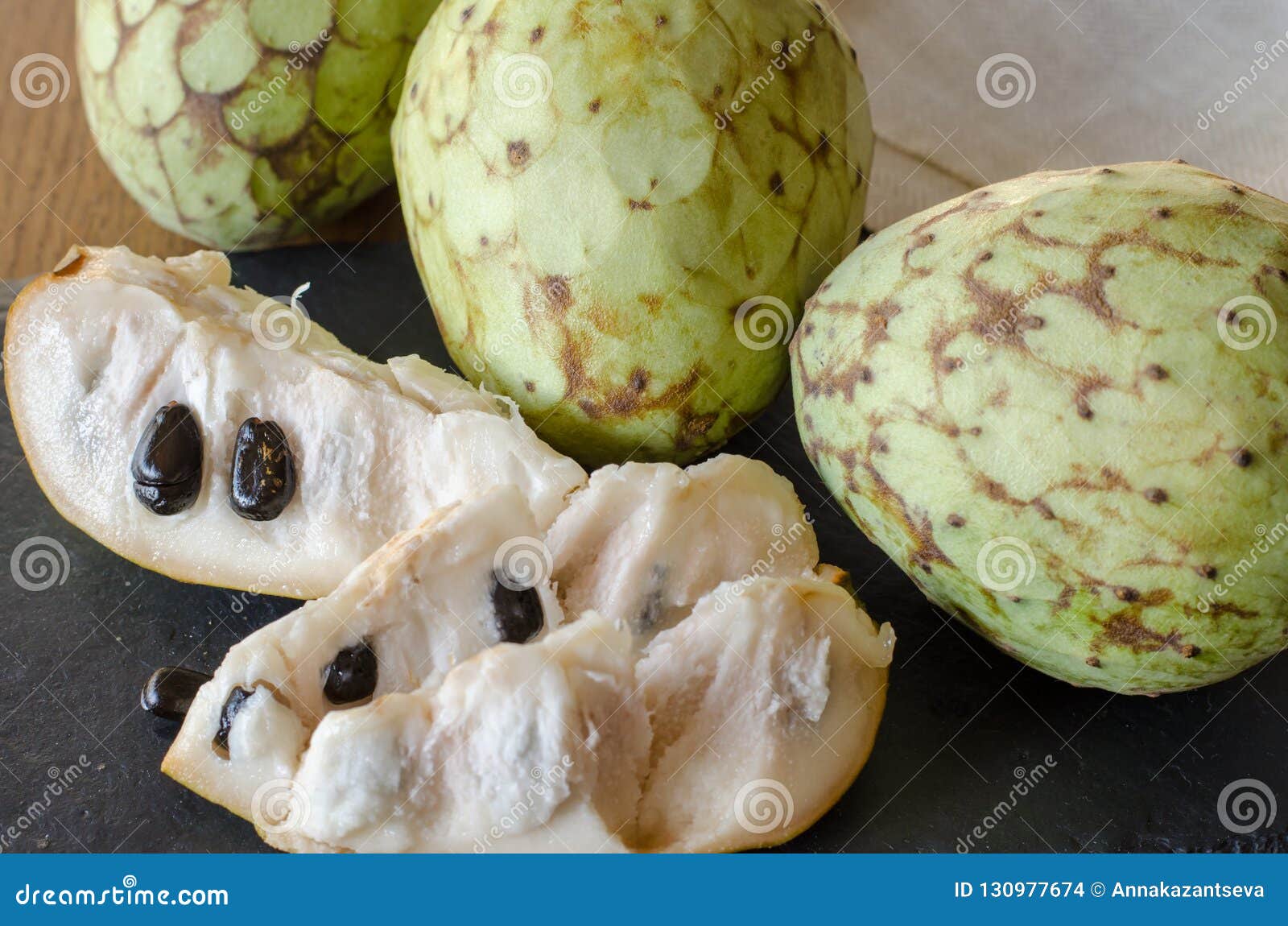 Cherimoya плода и немногие куски на черном каменном столе конец вверх