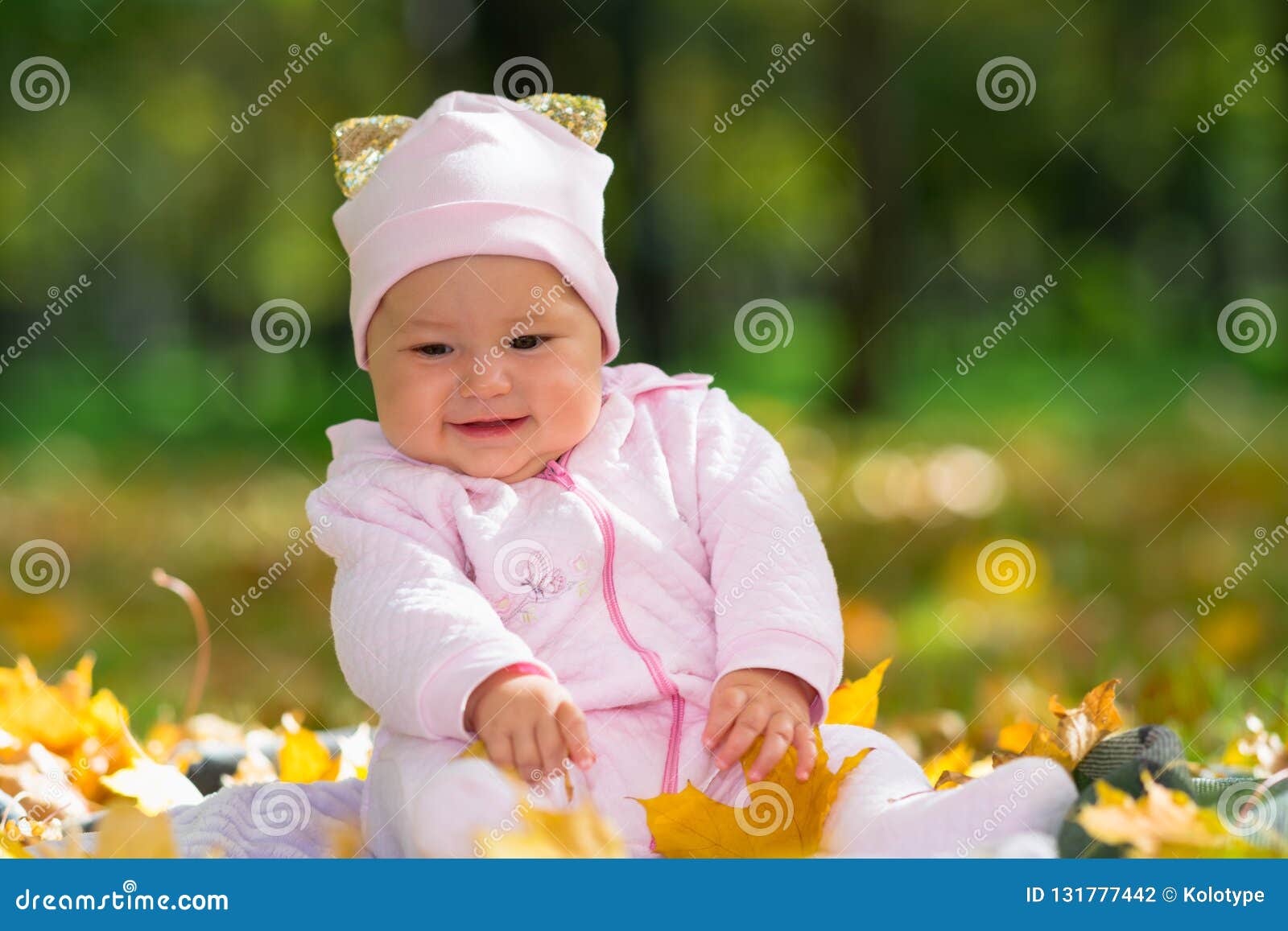 cherubic baby girl playing with yellow leaves.