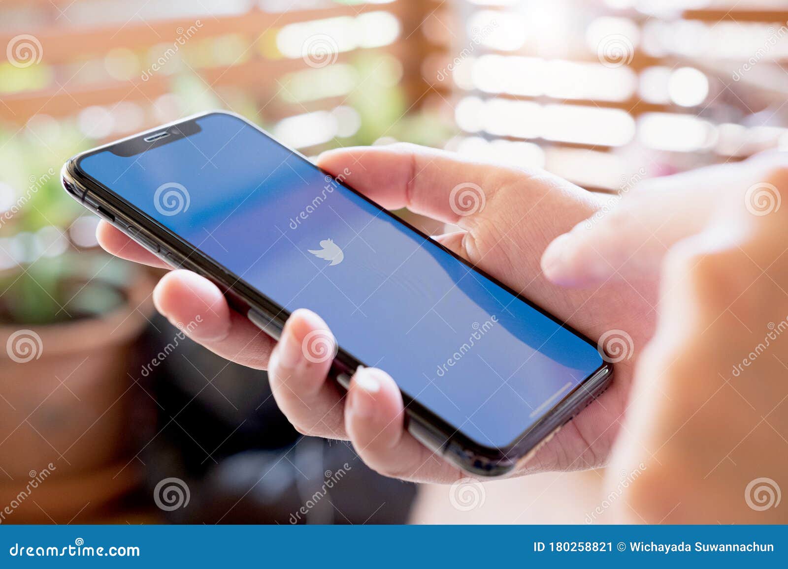 CHIANG MAI, THAILAND - JUL 28 2019: Woman holding I phone Xs with Twitter app on the screen.Twitter is an online news and social networking service where users post and interact with messages