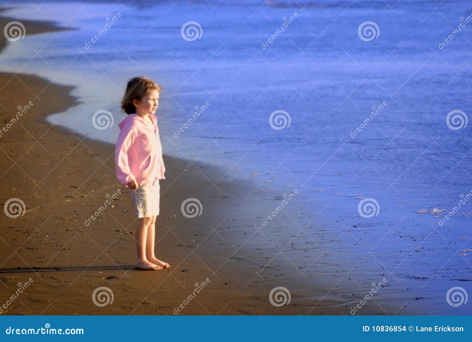 Chica joven en la playa. Chica joven que se coloca en la playa que mira el océano