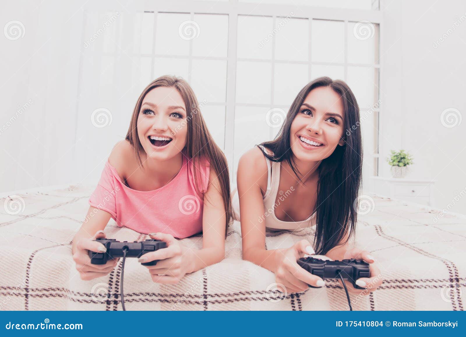 Chicas Felices Y Emocionadas Tendidas En El Dormitorio Y Jugando Videojuegos Foto De Archivo