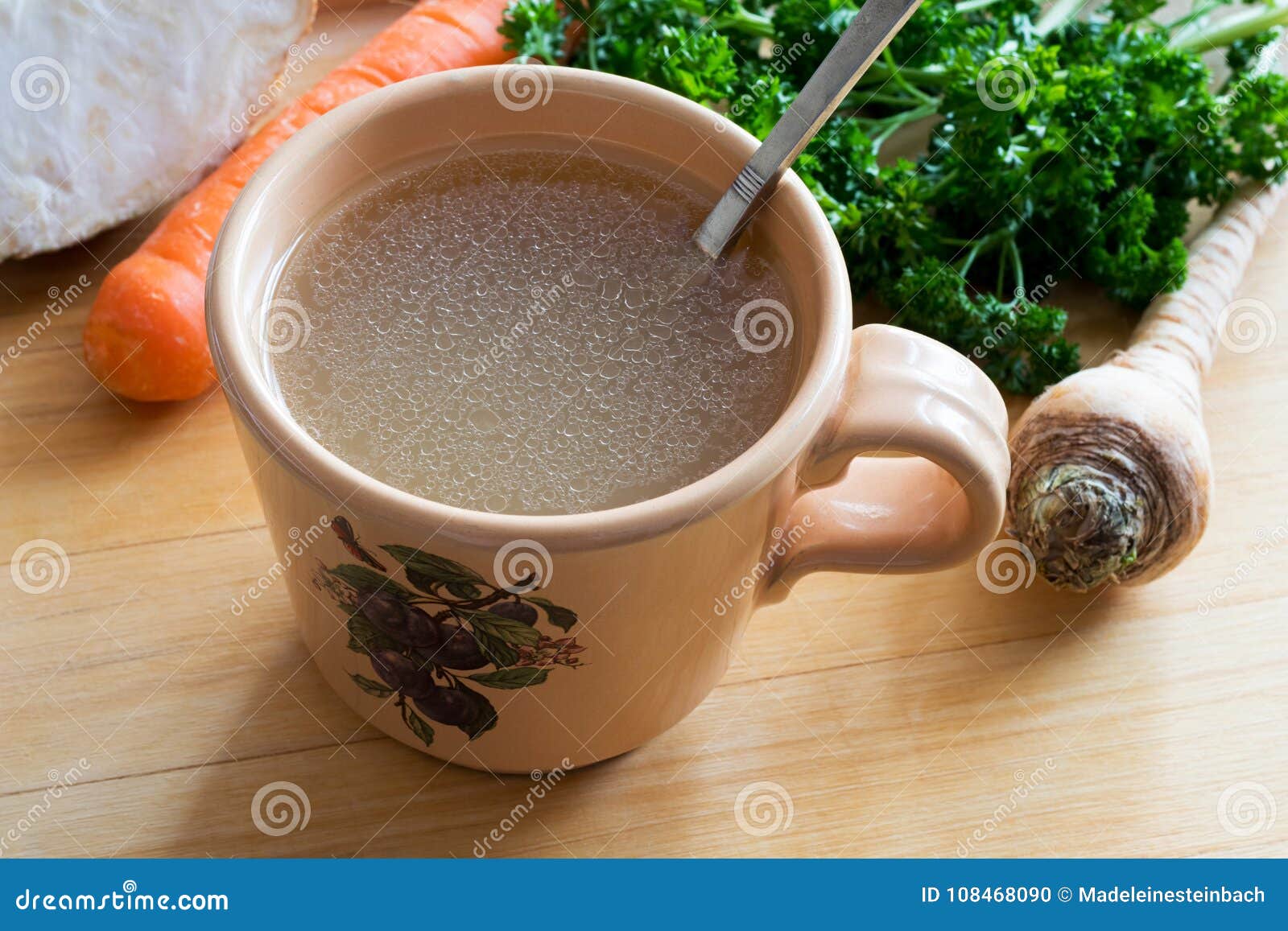 Chicken Bone Broth in a Mug with Vegetables in the Background Stock