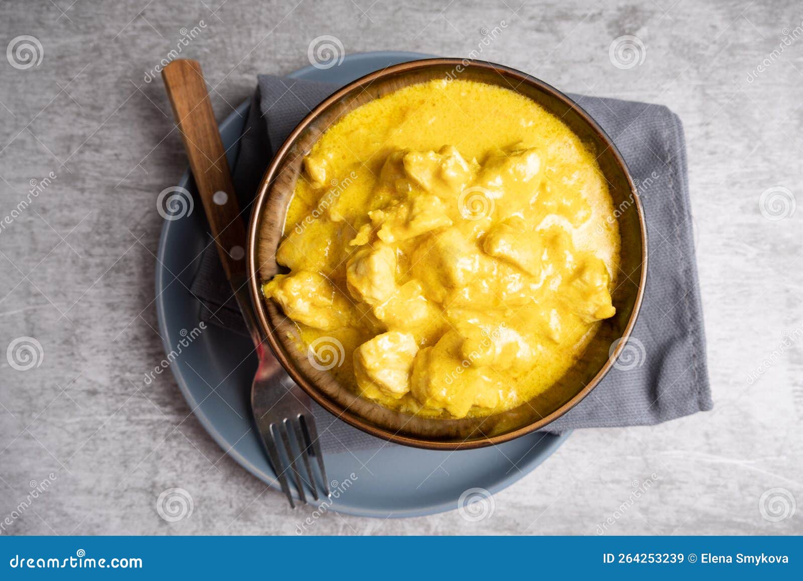 Chicken Cooked in Curry Sauce in a Bowl on a Blue Plate with a Fork