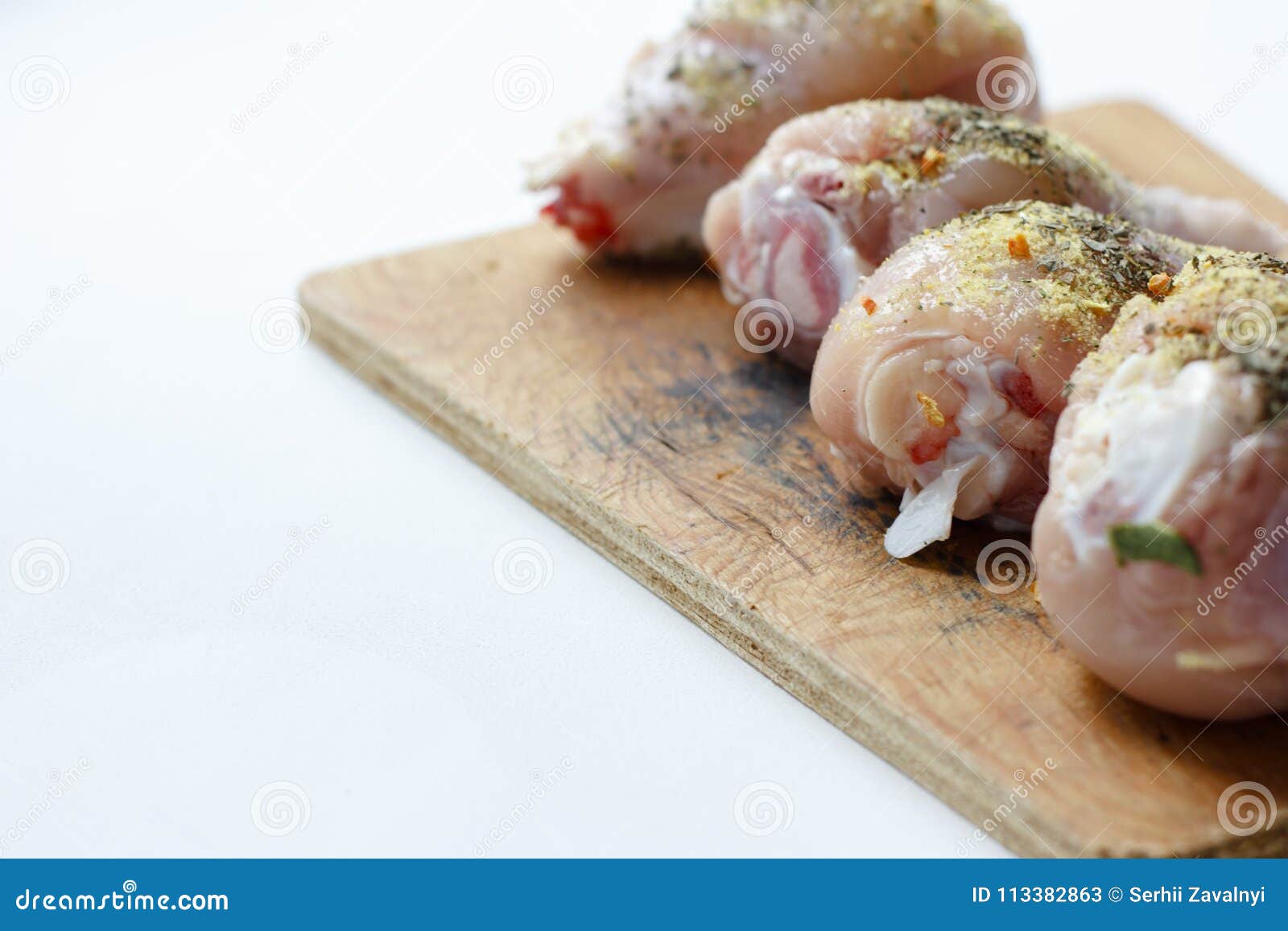 chicken drumsticks on a wooden board. on white,  background.top view. flat lay.