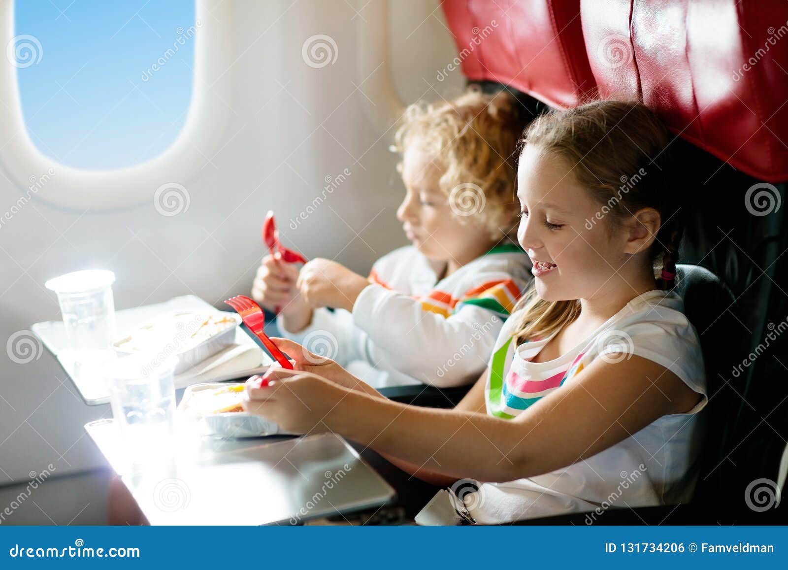 child in airplane window seat. kids flight meal. children fly. special inflight menu, food and drink for baby and kid. girl and