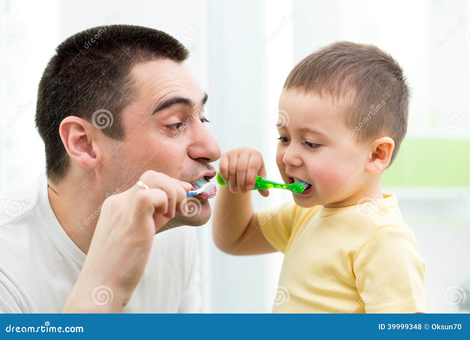 Child boy and his dad brushing teeth in bathroom