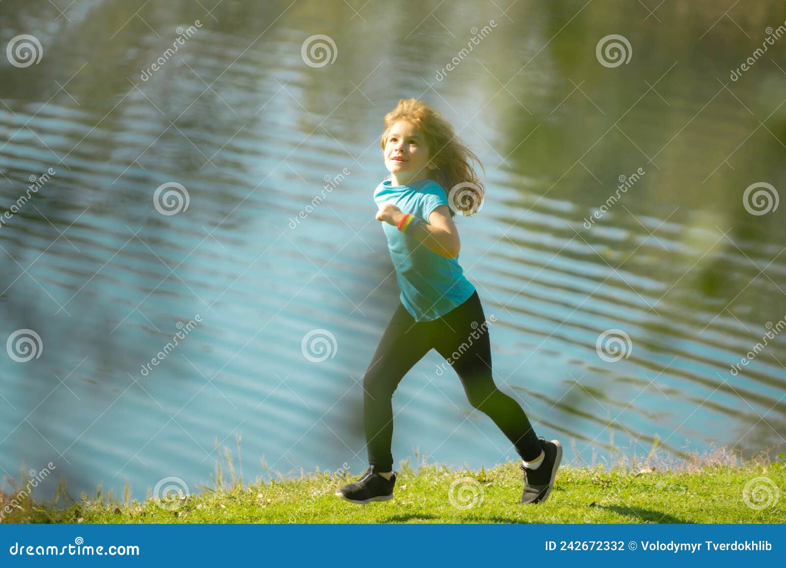 Child boy running or jogging near lake on grass in park. Sporty boy runner running in summer park. Active kids, sport children. Active energetic childhood