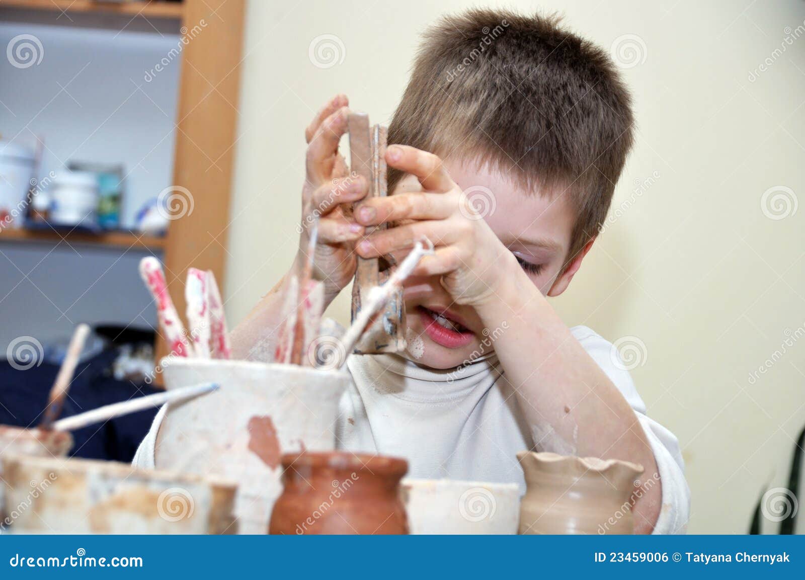 child boy shaping clay in pottery studio