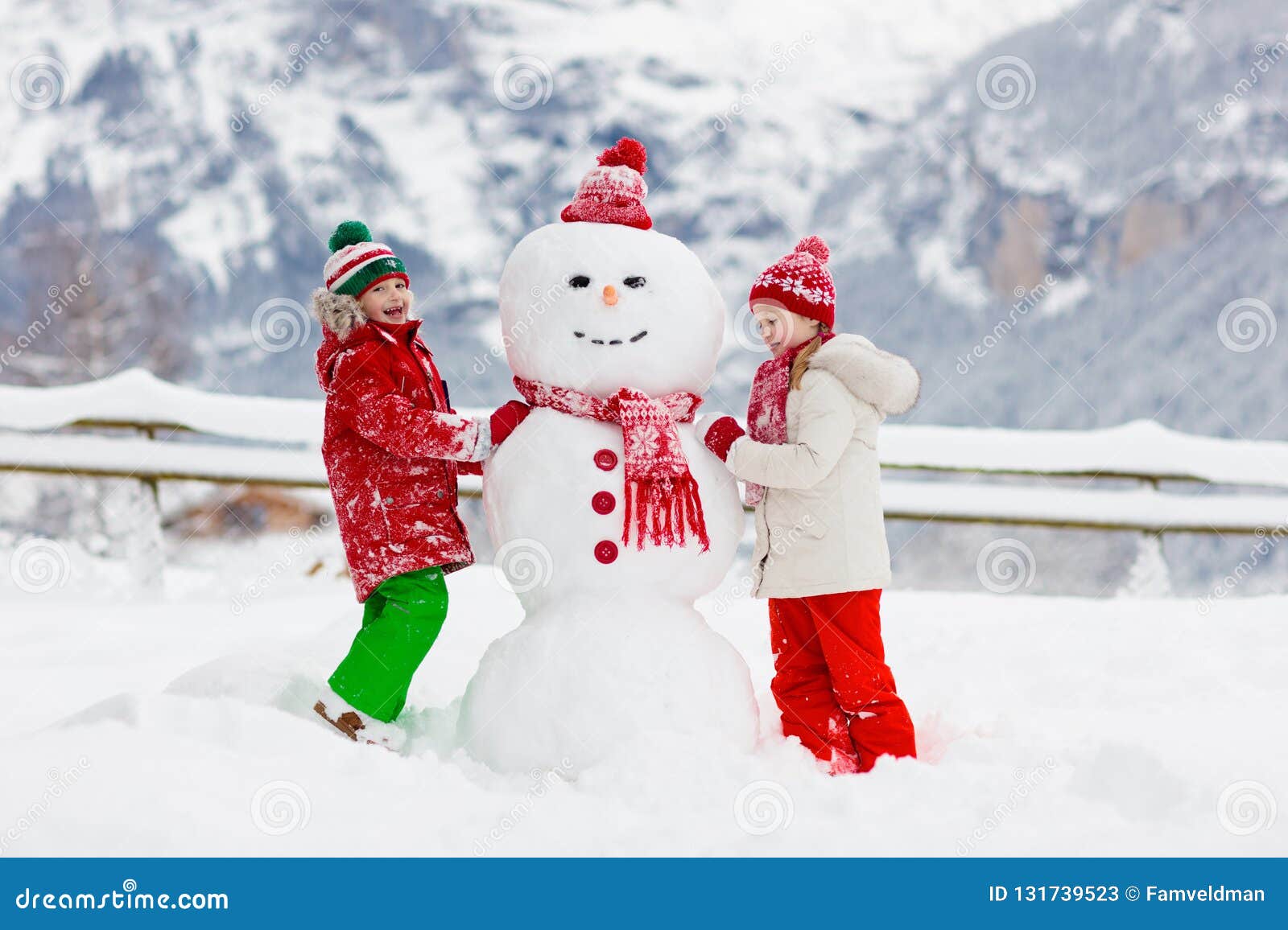 child building snowman. kids build snow man. boy and girl playing outdoors on snowy winter day. outdoor family fun on christmas