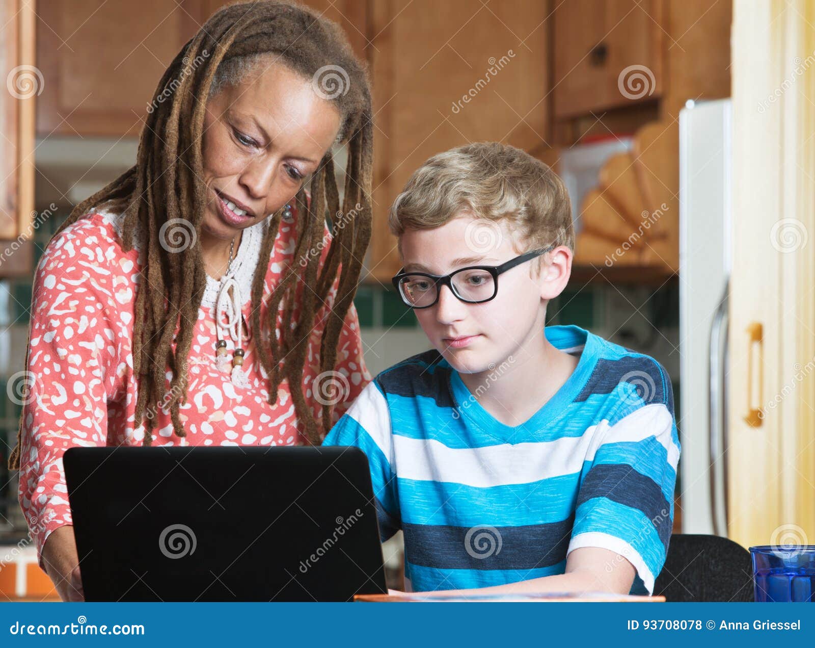 child doing homework with foster parent in kitchen